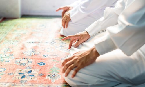 Muslim men praying in Tashahhud posture